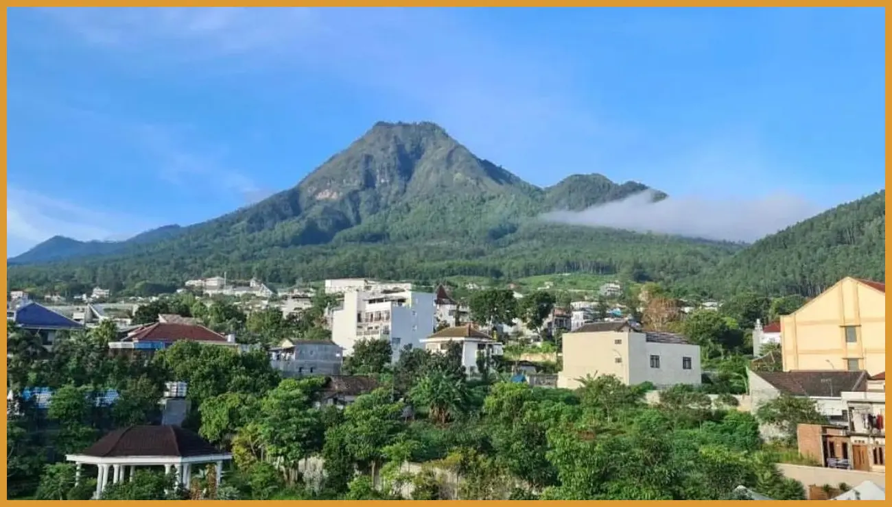 Sudut estetik di balkon glamping dengan latar kabut tipis yang menyelimuti perbukitan di pagi hari sambil memegang cangkir kopi hangat.