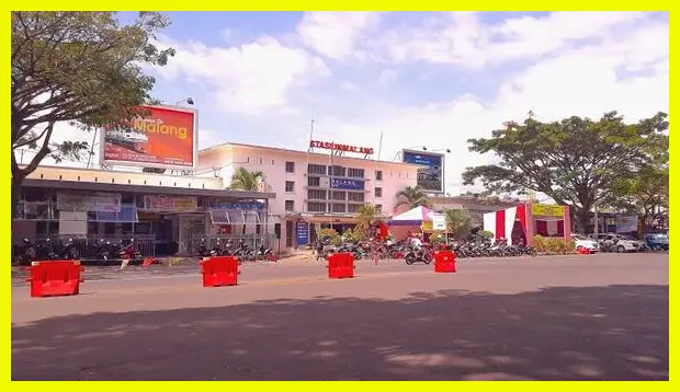 Potret barisan angkot biru yang terparkir rapi di depan stasiun atau terminal untuk menangkap esensi transportasi lokal khas Malang.
