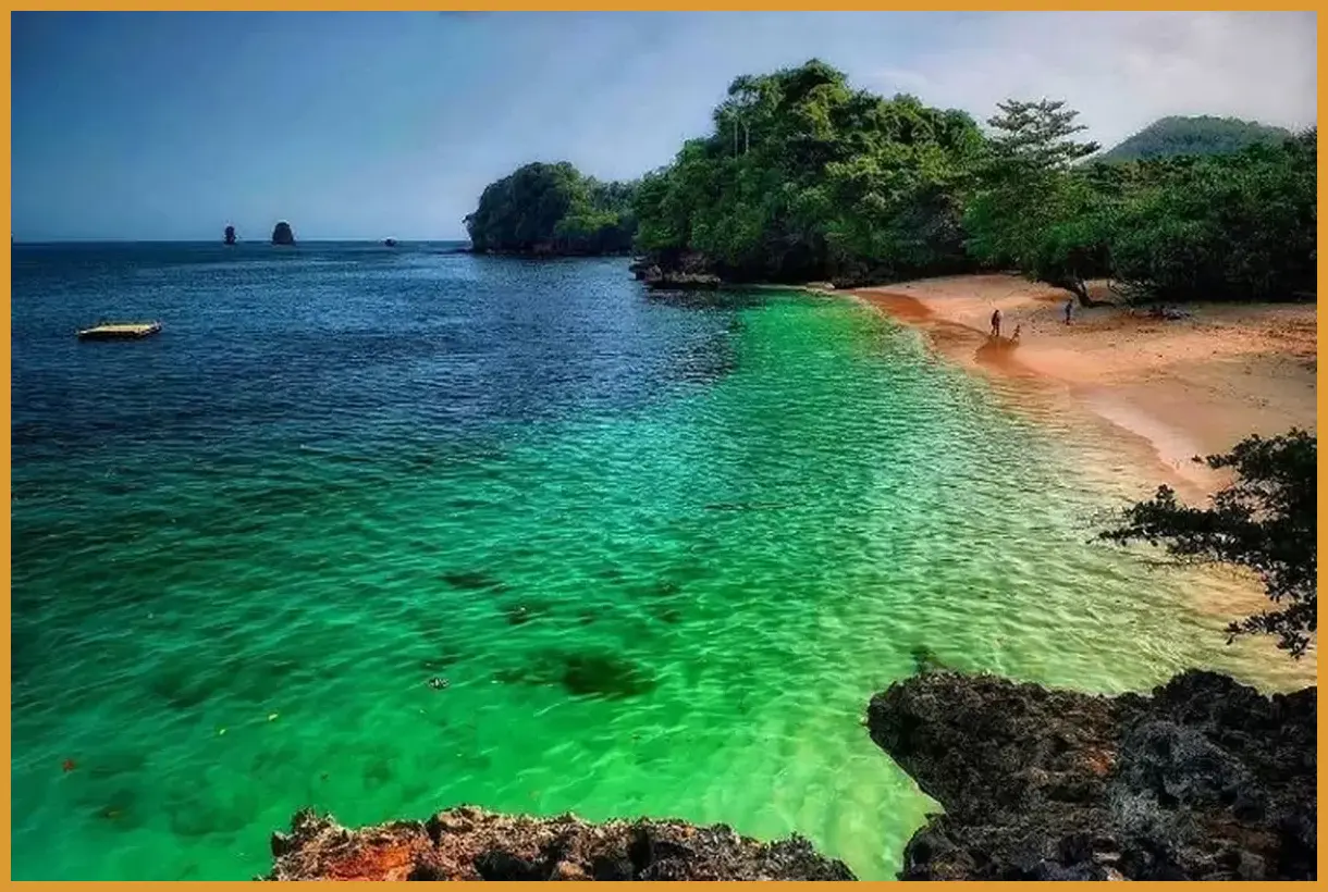 Ambil sudut pandang dari atas bukit sebelum turun ke pantai untuk menangkap gradasi tiga warna air laut yang kontras dengan pasir putih.