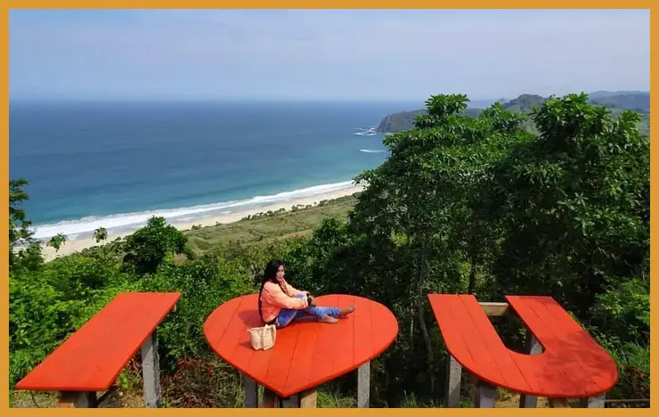 Ambil posisi dari bukit kecil di sisi timur pantai untuk mendapatkan sudut pandang tinggi yang memperlihatkan gradasi warna air laut dari bening, hijau, hingga biru tua.