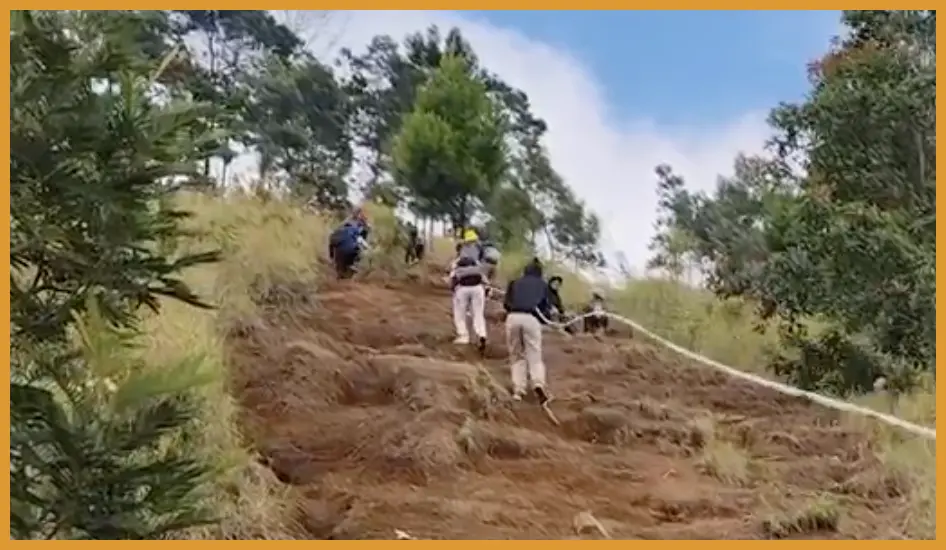 Tangkap momen ekspresi para pelari saat melewati tanjakan berbatu di kawasan Budug Asu dengan latar belakang puncak Gunung Mahameru yang terlihat gagah saat cuaca cerah.