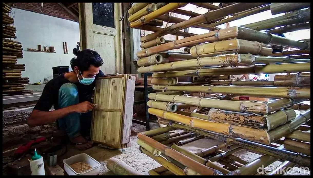 Ambil foto close-up tumpukan cenil warna-warni di atas nampan bambu (tampah) dengan latar belakang aktivitas pedagang pasar yang sibuk.