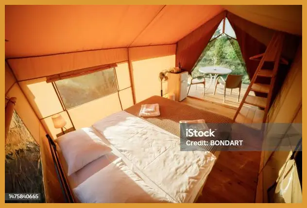 Foto dari dalam tenda glamping saat pintu dibuka, membingkai pemandangan matahari terbit yang muncul di sela-sela gugusan pulau kecil di Teluk Asmara.
