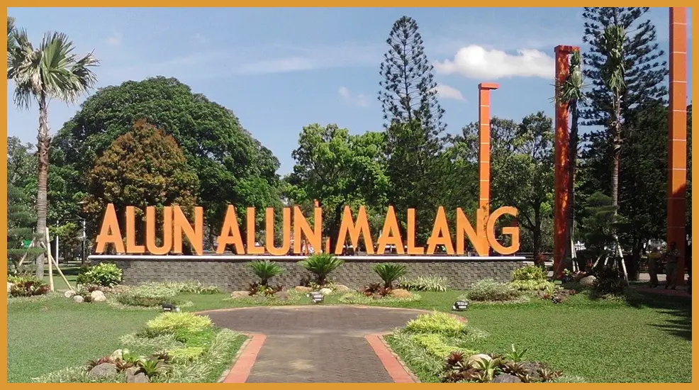 Potret candid suasana traveler yang sedang bersantai dengan latar belakang monumen Tugu Malang yang terlihat samar dari kejauhan di waktu fajar.